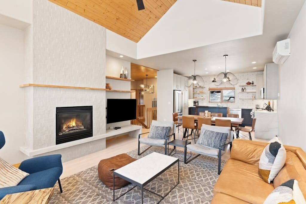 Una sala de estar moderna con chimenea, televisor y zonas de estar.