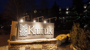 A sign with the word 'Kutuk' and a bear design, set on a stone base with a stone wall in the background. - Kutuk 101 - First-Floor Condo with Shared Hot Tub, WiFi, Gas Fireplace, and Full Kitchen (Steamboat Springs)