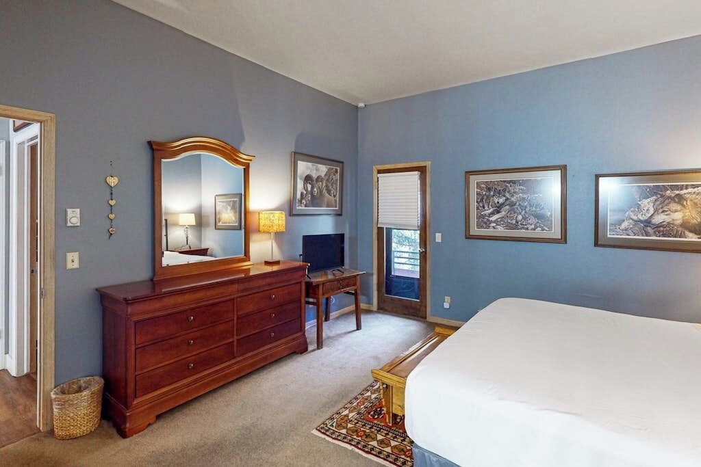 A bedroom with a bed, dresser, mirror, and artwork on the walls.