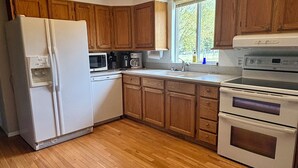 Eine Küche mit Holzausstattung, Kühlschrank, Mikrowelle, Kaffeemaschine und Backofen.