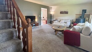 Ein Wohnzimmer mit Treppe, einer Couch, einem Couchtisch und einem Kamin.
