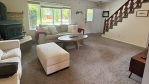 Ein Wohnzimmer mit Kamin, einer Couch, einem Couchtisch und einer Treppe.