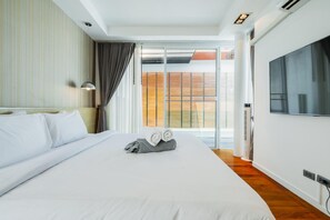 Ein Hotelzimmer mit einem großen Bett, einem Flachbildfernseher und einer Schiebet ür zu einem Balkon.