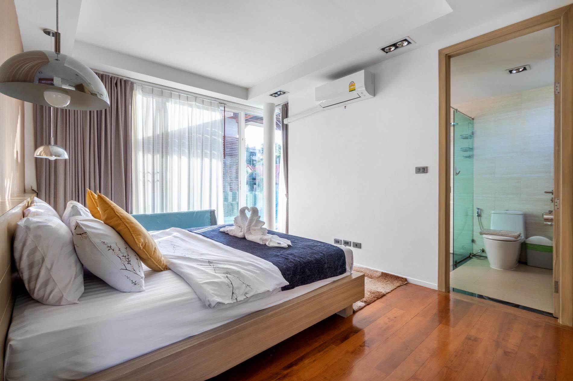 Une chambre d’hôtel moderne équipée d’un lit, d’une fenêtre avec des rideaux, d’un appareil de climatisation et offrant une vue sur la ville.