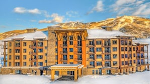 Ein mehrstöckiges Hotel mit Balkonen, einer überdachten Außenlounge und einer Bergkulisse.