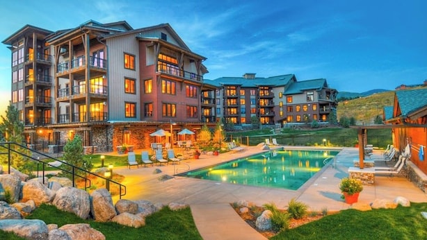 Ein mehrstöckiges Hotel mit Schwimmbad, Außenbereich und gepflegtem Rasen.