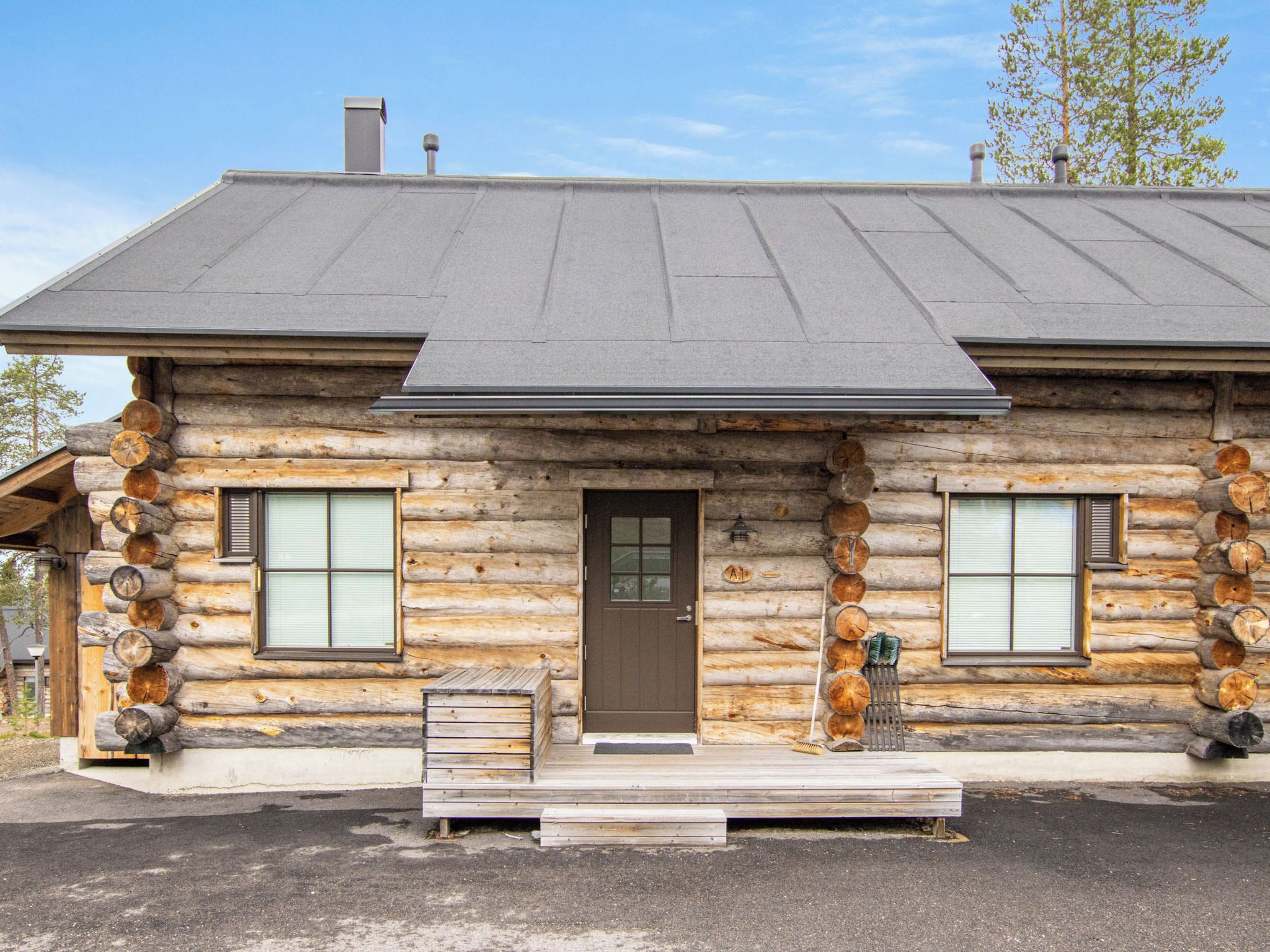 A log cabin with a front door, two windows, and a chimney.