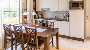 Una cucina moderna con mobili bianchi, un tavolo da pranzo in legno e un forno a microonde integrato.