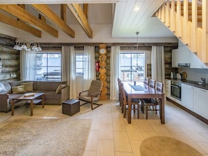 Un salón espacioso con techo de madera, una mesa de comedor con sillas, un sofá y una chimenea.