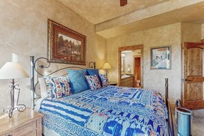 Un dormitorio con cama, lámparas de noche, un cuadro enmarcado, un espejo y un póster en la pared.