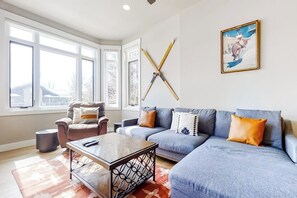 Ein Wohnzimmer mit Sofa, Sessel, Couchtisch und einem Bild an der Wand.