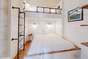 Ein Zimmer mit einem Etagenbett, einer Leiter, einem kleinen Tisch und einem gerahmten Bild an der Wand.