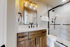 A bathroom with a white sink, wooden vanity, a mirror, and a glass shower enclosure. - Ski view condo walkable to the lifts with pools, hot tubs, WiFi, and fireplace (Steamboat Springs)