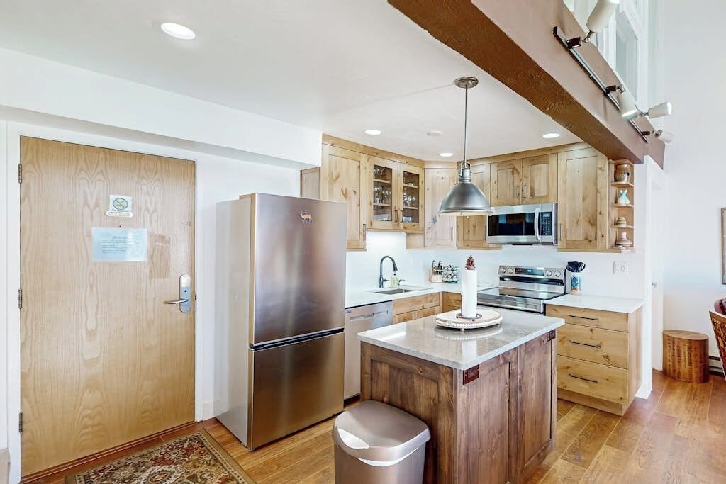 A modern kitchen with wooden cabinets, stainless steel appliances, and a central island.
