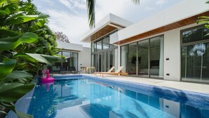 Uma casa moderna com piscina, amplas portas de vidro e área de varanda.
