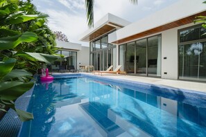 Ein modernes Haus mit Swimmingpool, großen Glasfenstern und einer Terrassenanlage.