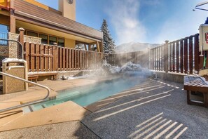 Ein Thermalbadbereich mit Holzzaun, Bänken und einem Gebäude im Hintergrund.