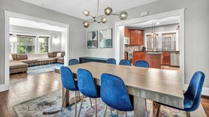 Un espace de salle à manger moderne avec une table en bois, des chaises bleues et un lustre.