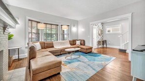 Un salon moderne avec un canapé d’angle, une table basse et un tapis à motifs.