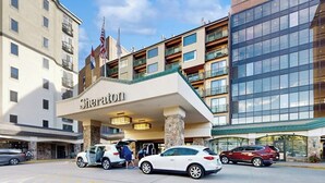 Um hotel Sheraton com entrada destacada, vários andares e uma bandeira.