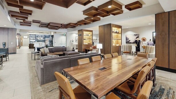 Um interior moderno com uma mesa de jantar de madeira, sofás e uma área de cozinha.