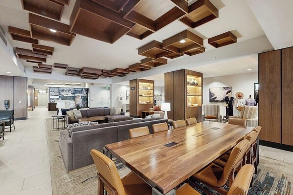 A modern interior with a wooden dining table, sofas, and a kitchen area. - Ski-in/ski-out condo in Sheraton with pool, hot tub, mountain view & fireplace (Steamboat Springs)