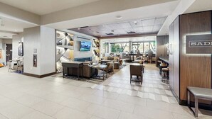 Um hall espaçoso com áreas de estar, balcão de recepção e uma grande janela com vista para o exterior.