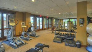 Ein Fitnessstudio mit Laufbändern, Crosstrainern, Kurzhanteln und Bänken.