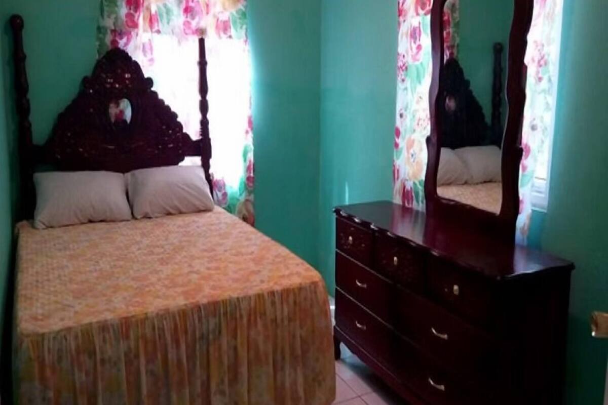 A bedroom with a bed, dresser, and mirror.