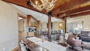 Ein geräumiger Wohnbereich mit Esstisch aus Holz, Ledersofas und einem Kronleuchter.