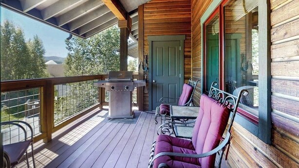 Eine Holzterrasse mit Grill, Sitzgelegenheit und Blick auf die umliegende Landschaft.