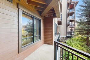 Ein Balkon mit Blick auf ein bewaldetes Gebiet, eine Holzfassade und ein Metallgeländer.
