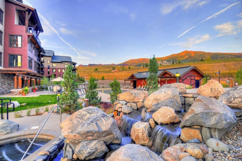 Um hotel com piscina, área de estar externa e uma cascata.