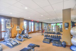 Ein Fitnessraum mit Laufbändern, Crosstrainern und einer Hantelbank.