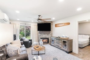 A living room with a fireplace, a ceiling fan, a television, and a sofa. - Ski-In/Ski-Out Condo with Shared Hot Tubs, Saunas, Patio, Shuttle to Ski Resort (Steamboat Springs)