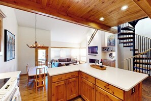 Eine moderne Küche mit Holzschränken, einer weißen Arbeitsplatte und einem Essbereich mit Tisch und Stühlen.
