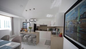 A modern kitchen with a central island, bar stools, a dining table, and a painting on the wall. - Perfect 3-bedroom Modern and Spacious Beach House (Manabí)