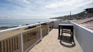 A balcony with a view of the beach and boats, a table, and a chair. - Perfect 3-bedroom Modern and Spacious Beach House (Manabí)
