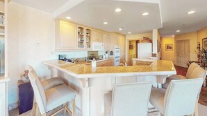 A kitchen with a central island, white cabinetry, and a dining area with chairs.