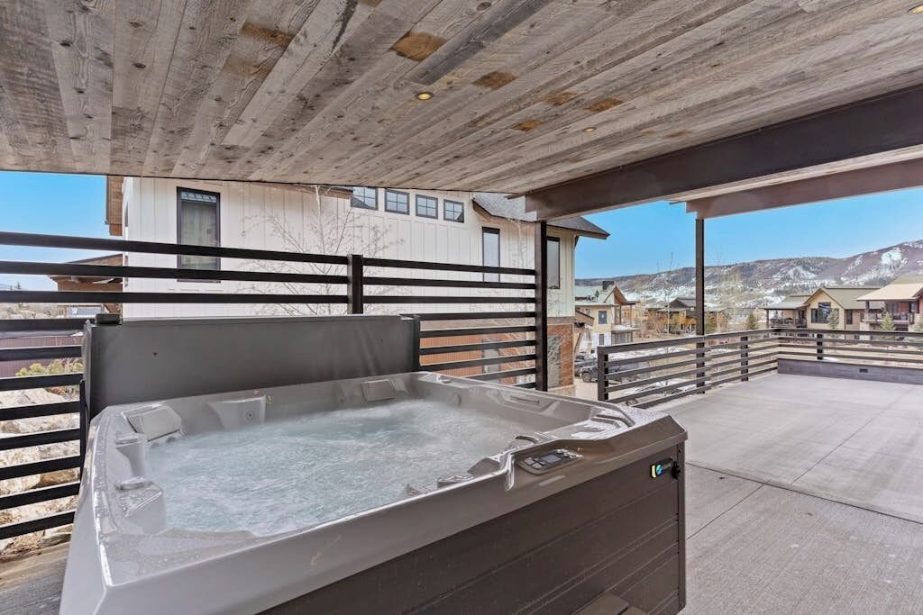 Ein Whirlpool auf einer Terrrasse mit Holzboden und Blick auf Gebäude im Hintergrund.