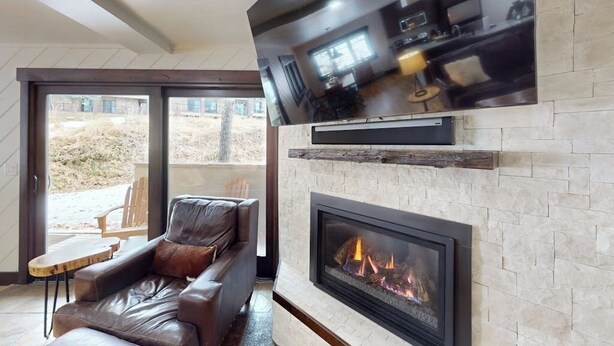 Una sala de estar moderna con chimenea, un sofá de cuero y un televisor de pantalla plana montado en la pared.