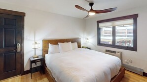 Un dormitorio con cama, ventilador de techo, ventana y puerta.