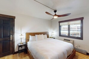 A bedroom with a bed, a ceiling fan, a window, and a door. - Cozy ski retreat with pool, hot tub, sauna, balcony & mountain views (Steamboat Springs)