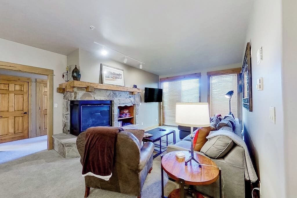 A living room with a stone fireplace, a television, a sofa, and a table.