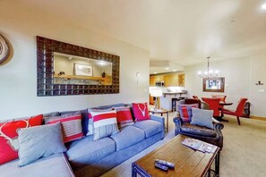 Ein Wohnzimmer mit einer Couch, einem Couchtisch und einem Essbereich mit einem roten Stuhl und Tisch.
