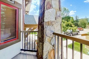 Ein Balkon mit Steinsäule, Holzwertlauf und einem Fenster mit Rollläden.