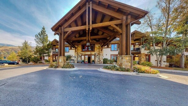 A lodge with a covered entrance, stone walls, and a parking area. - EagleRidge Lodge 210 Mountain view condo with pool, hot tubs & gym - short walk to gondola (Steamboat Springs)