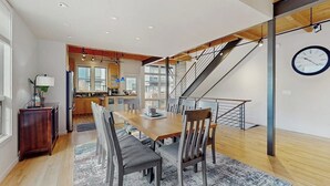 Una cocina moderna con comedor, suelo de madera y una escalera.