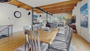 Un comedor moderno con una mesa de madera, asientos a rayas y vistas a la cocina y el comedor.
