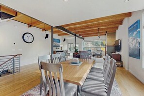 Ein moderner Essbereich mit Holztisch, gestreifter Sitzbank und Blick auf die Küche und den Essraum.